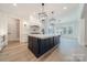 A modern, open kitchen with a large island, statement lighting, and stainless steel appliances at 310 Sugar Maple Ln, Weddington, NC 28104