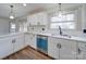 Well-lit kitchen boasts white cabinets, modern hardware, stainless steel dishwasher, and hardwood flooring at 337 Glenwood Dr, Mooresville, NC 28115