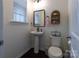 Charming half bath features a pedestal sink, decorative mirror, and toilet with stylish fixtures and finishes at 1019 Archibald Ave, Fort Mill, SC 29708