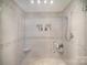 Newly tiled glass shower featuring a shower head and two shelves at 1300 Reece Rd # 200, Charlotte, NC 28209