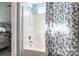 Bathroom shower with bright, white tile, a blue floral curtain, and chrome fixtures at 1515 Kingdom Way, Indian Land, SC 29707