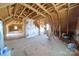 Large unfinished attic with exposed wooden beams, insulation, and a partially framed room at 175 Riley'S Dr, Salisbury, NC 28146