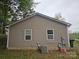 Back exterior view of a light brown home showing siding, two windows, and an air conditioning unit at 5315 Airport Dr, Charlotte, NC 28208