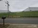 View from the road of a commercial building with utilitarian design, set behind a fence with a grassy hillside at 5315 Airport Dr, Charlotte, NC 28208
