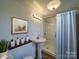 A decorated bathroom featuring a pedestal sink, glass-enclosed shower, and stylish accessories at 704 Mill St, Albemarle, NC 28001