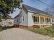 Home featuring newly installed gray siding, brick foundation, and a spacious gravel parking area at 704 Mill St, Albemarle, NC 28001