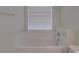 Bright bathroom featuring a white tub with a tile surround and a window with blinds at 8353 Emily Dr, Harrisburg, NC 28075