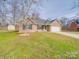 Brick home with green lawn, storage shed, and a driveway that leads to an attached two-car garage at 8353 Emily Dr, Harrisburg, NC 28075