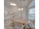 Bright eat-in kitchen with white cabinetry, appliances, and a center light fixture over the wooden table at 8353 Emily Dr, Harrisburg, NC 28075