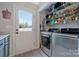 Bright laundry room with stainless steel washer/dryer, storage shelves, and backyard access at 8701 Gainsford Ct, Charlotte, NC 28210