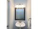Cozy powder room with a pedestal sink, decorative mirror and modern lighting at 13807 Queenswater Ln, Charlotte, NC 28273