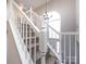 Carpeted staircase with a white railing and a decorative light fixture near an arched window at 13807 Queenswater Ln, Charlotte, NC 28273
