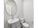 Well-lit half bathroom featuring a pedestal sink, round mirror, and white toilet at 1411 Windy Park Dr, Stanley, NC 28164
