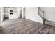 Open-concept living room boasts modern gray flooring, a view into the kitchen, and a carpeted staircase at 1411 Windy Park Dr, Stanley, NC 28164