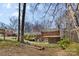 A home's backyard with mature trees, firepit, screened porch, deck, and grass at 211 Kingsway Cir, Charlotte, NC 28214
