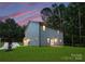 Exterior side and rear view of home with a green lawn at dusk, and a pink sky at 3117 Williams Rd, Matthews, NC 28105