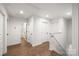 Hallway with wood flooring, white walls, doors and trim, and stairs with white banister and trim at 3117 Williams Rd, Matthews, NC 28105