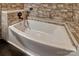 Close-up of a sleek bathtub with stone surround and dark fixtures, creating a spa-like atmosphere at 415 E Richland St, Kershaw, SC 29067