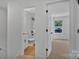 Hallway view to an all white bathroom with black fixtures, a tiled shower and vinyl floor at 425 Messner St, Salisbury, NC 28144