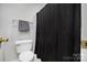 Close-up of a toilet and dark shower curtain, accented by a gray towel on a towel bar at 4507 Antelope Ln, Charlotte, NC 28269