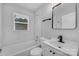 Modern bathroom features marble-patterned tiling, tub-shower combo, sleek vanity, and black fixtures at 5028 Wilgrove Mint Hill Rd, Mint Hill, NC 28227