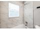 Bright bathroom shower featuring marble-patterned tile, adjustable shower head, and a window at 5028 Wilgrove Mint Hill Rd, Mint Hill, NC 28227