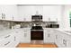 A modern kitchen with white cabinets, stainless steel appliances, and quartz countertops at 5404 Maplewood Ln, Charlotte, NC 28227