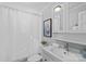 Bright bathroom features a single sink vanity, framed mirror, and shower with white shower curtain at 701 S Torrence St, Charlotte, NC 28204