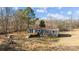 Single-story home boasts navy siding, brown roof, and a spacious wooden deck with stairs in a serene setting at 1254 Raxter Rd, Edgemoor, SC 29712