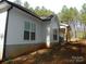 Side view of a house with white siding and black gutters surrounded by trees in a wooded lot at 128 Summerlake Dr, New London, NC 28127