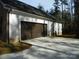 Attached two car garage with dark wood door and driveway, surrounded by a large lawn and trees at 128 Summerlake Dr, New London, NC 28127