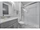 A modern bathroom features a glass enclosed shower, gray vanity with countertop, and tiled floor at 16709 Mckee Rd, Charlotte, NC 28278