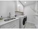 Well-lit laundry room featuring white cabinets, modern appliances, and a stylish sink at 16709 Mckee Rd, Charlotte, NC 28278