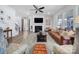 Bright living room features a ceiling fan, fireplace with TV, leather sofa, and neutral color palette at 16709 Mckee Rd, Charlotte, NC 28278