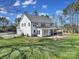 Rear exterior view of a two-story white home with a patio, fire pit, grassy yard, and mature trees at 16709 Mckee Rd, Charlotte, NC 28278
