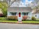 Charming light blue home featuring a welcoming front porch, vibrant landscaping, and a red front door at 253 Misenheimer Nw Dr, Concord, NC 28025