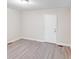 A simple bedroom features grey wood-look flooring, white walls, white trim, and a door at 712 Stevens St, Gastonia, NC 28054