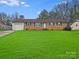 Charming single-story brick home featuring a well-manicured lawn and attached garage on a sunny day at 712 Stevens St, Gastonia, NC 28054