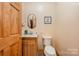 Half bath with a wooden vanity, oval mirror, and toilet at 809 Liberty Rd, Gold Hill, NC 28071