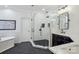 Bright bathroom featuring a soaking tub, glass shower, black fixtures, and double sinks with white counters at 9128 Summer Club Rd, Charlotte, NC 28277