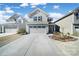 Charming two-story home with a spacious driveway, manicured lawn, and landscaping at 14032 Canemeadow Dr, Charlotte, NC 28278