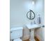 Cozy half bathroom featuring a pedestal sink, round mirror, and a toilet with wooden floors at 324 Wendover Hill Ct, Charlotte, NC 28211