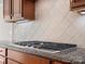 Close up of a stainless gas cooktop with granite countertops and tile backsplash at 4030 Ambleside Dr, Fort Mill, SC 29707