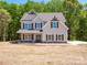 Charming two-story home featuring gray siding, brown shutters, and a well-manicured lawn and a backyard forest at 5311 Meadowland Pkwy, Monroe, NC 28112