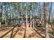 Brick home featuring a deck and patio, surrounded by mature trees and fencing at 693 Emerald Shores Rd, Mount Gilead, NC 27306