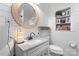 Cozy bathroom featuring a large, round mirror, white tiled walls, granite countertop, and lovely decorations at 693 Emerald Shores Rd, Mount Gilead, NC 27306