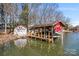 Covered boat dock featuring boat lift and adjacent storage shed on the lake at 693 Emerald Shores Rd, Mount Gilead, NC 27306