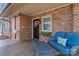 Covered front porch with a blue cushioned wicker couch and brick home exterior at 693 Emerald Shores Rd, Mount Gilead, NC 27306