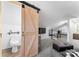 Spacious living room with plush carpeting, a gray sofa, and a toilet behind a sliding barn door at 693 Emerald Shores Rd, Mount Gilead, NC 27306