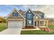 Beautiful two-story home featuring a stone facade, blue accents, a two-car garage, and manicured lawn at 7033 Sylvan Retreat Dr, Denver, NC 28037